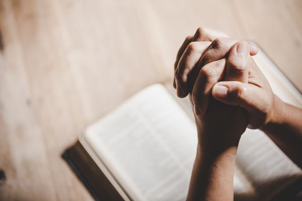 praying hands over a bible