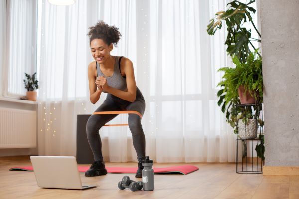 woman doin squats with resistance band in her home